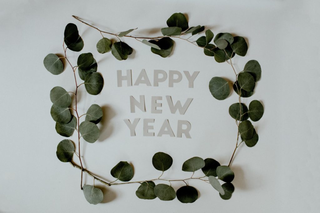 Eucalyptus leaves surround a "Happy New Year" message, another example of inclusive holiday greetings.