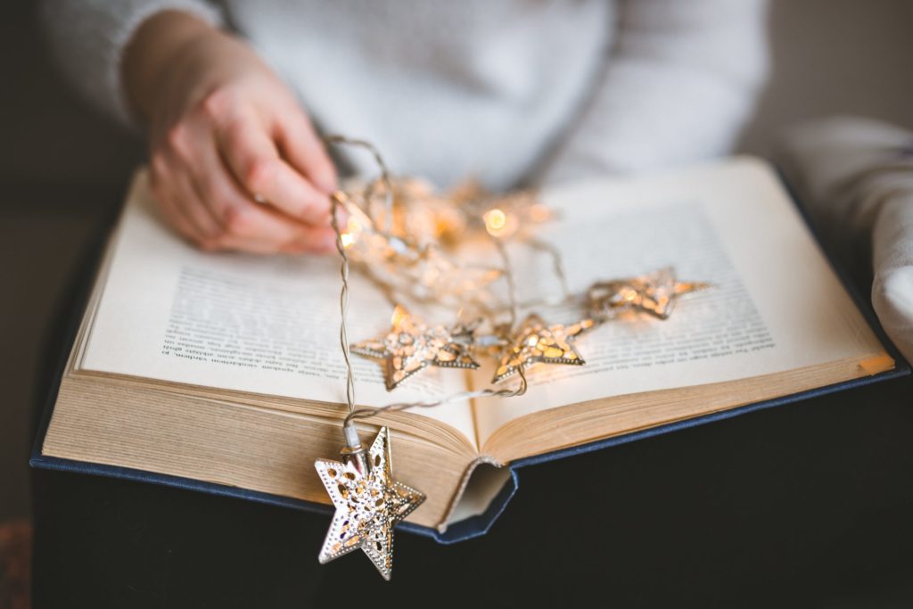 An open book with holiday lights on top. Read on for more inclusive holiday greeting resources you won't want to miss!