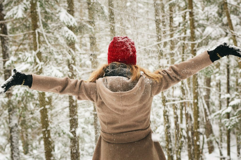 A woman with arms outstretched by a snowy landscape. It's sort of the perfect picture for inclusive holiday greetings because it looks like she's embracing the season! 