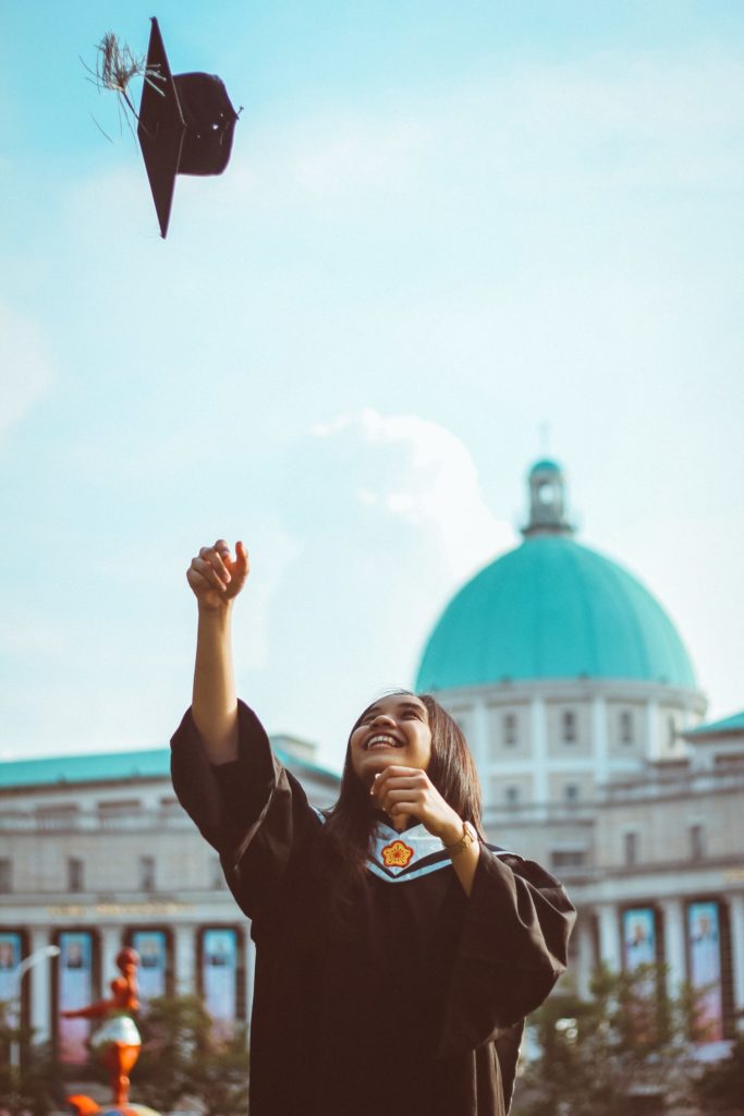 A happy college grad throws her cap into the air.