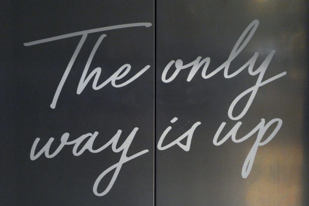 Elevator doors read, "The only way is up."